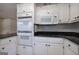 Kitchen featuring white cabinets, black countertops, and built in ovens with stainless steel appliances at 668 Spring Place Ne Rd, White, GA 30184