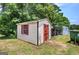 Exterior shot of a small outbuilding featuring painted trim, a window, and door adjacent to a green garbage container at 668 Spring Place Ne Rd, White, GA 30184