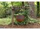 Unique yard decor featuring a hanging cauldron on a wooden trellis within a wrought iron fence and lush greenery at 2179 Mountclaire Ct, Stone Mountain, GA 30087