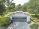 Detached garage with gray doors and a concrete driveway, surrounded by mature trees and landscaping at 306 Tyrone Rd, Fayetteville, GA 30214
