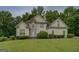 Beautiful two-story home boasts a stone facade, well-manicured lawn, and lush landscaping at 235 Rustic Mill Ln, Fayetteville, GA 30214