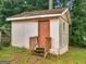 Exterior view of the storage shed with wooden steps and a window set amongst mature trees at 8310 Meridian Dr, Riverdale, GA 30274