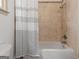 Bathroom boasting a shower-tub combination with tile walls and black and white curtain at 187 Vanira Se Ave, Atlanta, GA 30315