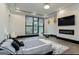 Relaxing bedroom featuring lots of natural light, tray ceiling, modern fireplace, and mounted TV at 2401 Ne Greenglade Rd, Atlanta, GA 30345