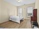 Cozy bedroom with a white poster bed, wood floors, natural light, and a desk area for work or study at 5825 Trailwood Ct, Suwanee, GA 30024