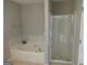 Bathroom featuring a white tiled tub, glass door shower and neutral colored walls, creating a calming and serene space at 5400 Twin Lakes Dr, South Fulton, GA 30349