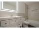 Modern bathroom featuring a white vanity with an illuminated mirror, toilet, and a tiled bathtub with shower at 4959 Abbotts Glen Nw Trl, Acworth, GA 30101