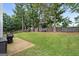 Spacious backyard featuring a lush lawn, patio area with a grill, and mature trees at 192 Sandhurst Ct, Suwanee, GA 30024