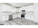 Well-lit kitchen featuring white cabinets, stainless steel appliances, granite countertops, and gray wood-look flooring at 3373 Arabian Farm Dr, Dacula, GA 30019