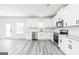 Modern kitchen with stainless steel appliances, white cabinets, and grey wood-look flooring at 3373 Arabian Farm Dr, Dacula, GA 30019