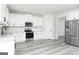 Modern kitchen boasts stainless steel appliances, white cabinets, granite counters, and stylish gray floors at 3373 Arabian Farm Dr, Dacula, GA 30019