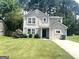 Charming two-story home featuring light beige paint, a well-manicured lawn, and beautiful landscaping at 6300 Creekford Ln, Lithonia, GA 30058