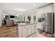 Open-concept kitchen with a center island, stainless steel refrigerator, and white cabinetry flowing seamlessly into the living area at 5662 Valley Loop, Fairburn, GA 30213