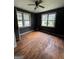 A bedroom with dark walls, wood floors, natural light, and two windows with views of the outdoors at 8373 Chicago Ave, Douglasville, GA 30134