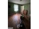 A dated bedroom with hardwood floors, drab green walls, and natural light from one small window at 8373 Chicago Ave, Douglasville, GA 30134