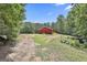 Exterior view of a red barn surrounded by trees with a dirt driveway at 6220 Petersburg Rd, Fairburn, GA 30213