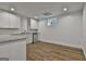 Basement kitchenette with white cabinets, granite counters, stainless mini-fridge and wood-look flooring at 6220 Petersburg Rd, Fairburn, GA 30213