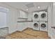 Well-lit laundry room with stackable washer and dryer, white cabinetry, and wood-look flooring at 6220 Petersburg Rd, Fairburn, GA 30213