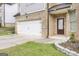 Attached two-car garage with white doors and concrete driveway, with a well-manicured lawn and landscaped flower beds at 2004 Brittlebank Ln, Lawrenceville, GA 30043