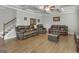 Comfortable living room featuring hardwood floors, a coffered ceiling, three leather sofas, and a staircase in the background at 2004 Brittlebank Ln, Lawrenceville, GA 30043