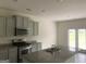 Modern kitchen with stainless steel appliances, granite countertops, a kitchen island with sink, and gray cabinets at 1636 Jersey Dr, Stockbridge, GA 30281
