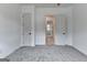 A simple bedroom with plush gray carpet and bright white walls leads to another room at 4090 Sandy Lake Dr, Lithonia, GA 30038
