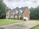 Traditional two-story brick home featuring an attached garage and a well-manicured lawn at 1433 Cotton Sw Trl, Conyers, GA 30094