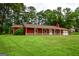Attractive red home with a covered porch and stone accents, nestled among lush trees and a vibrant green lawn at 125 Point View Ct, Tyrone, GA 30290
