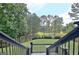 View of the backyard with manicured lawn, black metal fence, and picturesque lake setting at 383 Beaumont Farms Dr, Sharpsburg, GA 30277