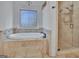 Bright bathroom boasts soaker tub with stone surround and frameless shower at 383 Beaumont Farms Dr, Sharpsburg, GA 30277