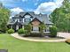 Well-manicured front lawn and landscaping of a stunning two-story home with a stone facade at 383 Beaumont Farms Dr, Sharpsburg, GA 30277