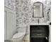 Chic powder room with floral wallpaper, black vanity, modern sink and elegant mirror above the toilet at 383 Beaumont Farms Dr, Sharpsburg, GA 30277