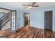 Bedroom with light blue walls, a ceiling fan, wood-look flooring, and a view of the staircase at 424 Browning Field Way, Hampton, GA 30228
