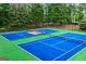 A green and blue outdoor community tennis court bordered by trees and greenery at 5833 Wembley Dr, Douglasville, GA 30135