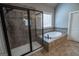 Bright bathroom offering a shower with glass doors and a separate tub beneath a large window at 6248 Sunshine Cove Ln, Buford, GA 30518