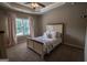 Neutral bedroom boasts a tray ceiling, ceiling fan, window and a cozy bed at 6248 Sunshine Cove Ln, Buford, GA 30518