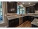 Bright kitchen features granite countertops, stainless appliances, tiled backsplash, and an abundance of dark wood cabinets at 6248 Sunshine Cove Ln, Buford, GA 30518