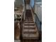Carpeted staircase with dark wood handrails and decorative iron spindles leads to the upper level of the home at 6248 Sunshine Cove Ln, Buford, GA 30518