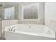 Close up of large soaking tub with tile surround and chrome fixtures at 266 Hanover Dr, Villa Rica, GA 30180