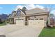 Three-car garage featuring paneled doors, stone and brown plank accents, and a wide driveway at 266 Hanover Dr, Villa Rica, GA 30180