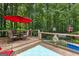 A wooden deck features a red umbrella over a table and chairs, offering a serene outdoor relaxation area at 103 Everhill, Peachtree City, GA 30269