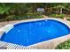 An in-ground swimming pool with clear blue water is surrounded by a concrete deck and lush greenery at 103 Everhill, Peachtree City, GA 30269