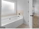Bright bathroom featuring a soaking tub with tile backsplash and window at 149 Elkins Blvd, Locust Grove, GA 30248