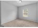 This bedroom offers a neutral carpet, blank walls, a window, and ample natural light at 149 Elkins Blvd, Locust Grove, GA 30248