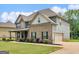 Charming two-story home featuring brick accents, lush landscaping, and a well-manicured lawn at 149 Elkins Blvd, Locust Grove, GA 30248