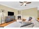 Well-lit living room featuring a plush sectional, a fireplace, modern furniture, and hardwood floors at 401 Buckboard Ln, Locust Grove, GA 30248
