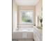 Bathroom featuring a soaking tub beneath a stained glass window, a white vanity, and brushed gold fixtures at 450 Riverwalk, Mcdonough, GA 30252