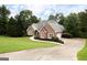 Charming brick home features a well-manicured lawn, lush trees, and a curved driveway for a welcoming entrance at 450 Riverwalk, Mcdonough, GA 30252