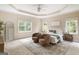 Large primary bedroom features tray ceilings, neutral carpeting, two chairs, and lots of natural light at 450 Riverwalk, Mcdonough, GA 30252