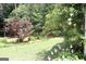 Lush green backyard featuring a well-maintained lawn, mature trees, and a variety of flowering plants, offering privacy at 405 Mallory Cir, Loganville, GA 30052